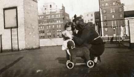 Et noe uskarpt bilde av Kristine Gullestad og en liten pike. Bildet er trolig tatt på taket på en boligblokk i en by. Se også de andre bildene av samme motiv, dvs. nr. Ua/L0001/0089-94.