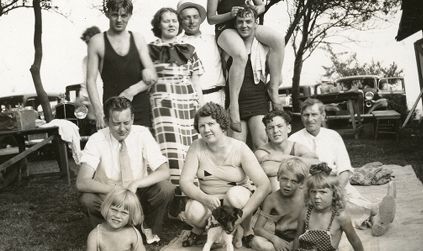 Barn og voksne samlet utendørs. Kristine Gullestad (kvinnen i rutete kjole i bakre rekke).
