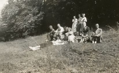 En gruppe yngre menn og kvinner sittende i en skråning. Ingeborg Gullestad er kvinnen i lys kjole som sitter i midten av bildet, til høyre for henne er søsteren, Kristine Gullestad