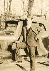 Mann i dress og frakk ved bil