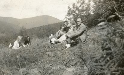 En gruppe yngre menn og kvinner sittende i en skråning. Kvinnen i midten til høyre i bildet er Ingeborg Gullestad. Kvinnen med mørkt hår som ligger til venstre i bildet er trolig Kristine Gullestad