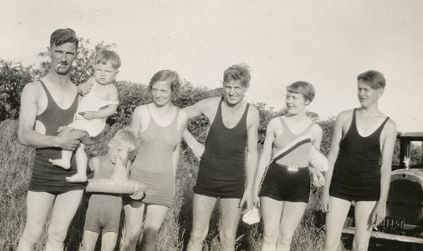 Tre menn, to kvinner og et barn i badetøy. Ingeborg Gullestad er kvinnen til høyre i bildet i badedrakt med stripe på.